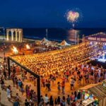 Vista aérea noturna da Vila do Forró no Arraiá do Povo 2026, com a Arena de Shows lotada sob o céu nublado de Aracaju.
