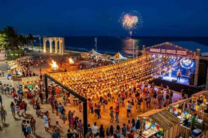 Vista aérea noturna da Vila do Forró no Arraiá do Povo 2026, com a Arena de Shows lotada sob o céu nublado de Aracaju.