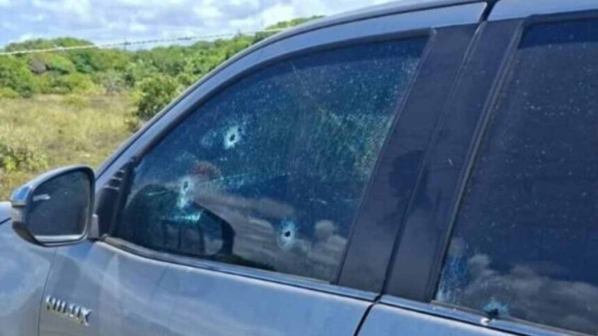 Veículo branco com marcas de perfuração de bala no para-brisa e portas na Praia do Abaís, em Estância.