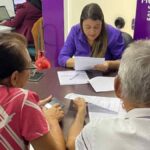 Família analisando contrato de compra de imóvel com maquete de casa sobre a mesa