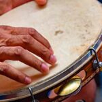 Um pandeiro decorado em primeiro plano, simbolizando o Samba de Terreiro.