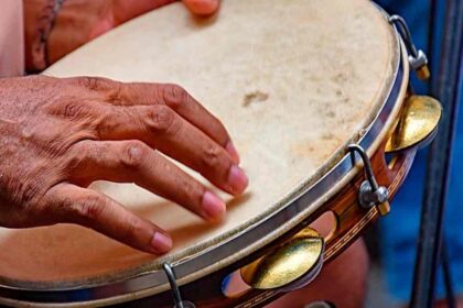 Um pandeiro decorado em primeiro plano, simbolizando o Samba de Terreiro.