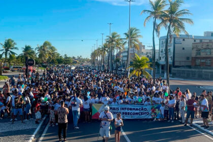 Participantes da 4ª Caminhada de Conscientização do Autismo em Aracaju segurando cartazes azuis na Orla de Atalaia.