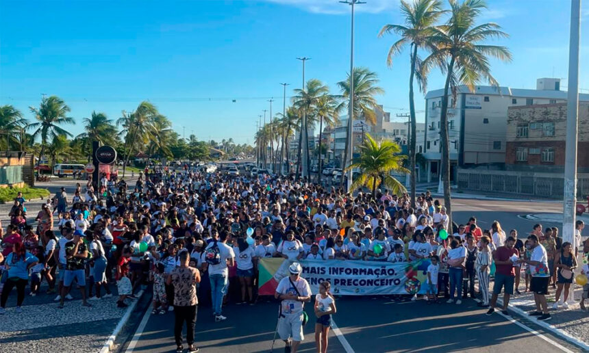 Participantes da 4ª Caminhada de Conscientização do Autismo em Aracaju segurando cartazes azuis na Orla de Atalaia.