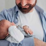 Pai segurando bebê recém-nascido, simbolizando a nova lei de licença-paternidade sancionada em 2026.