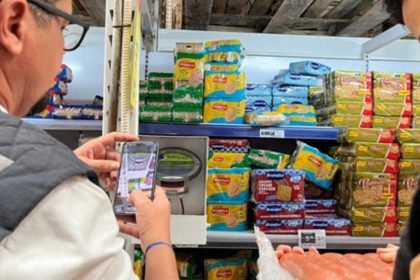 Fiscais do Procon Sergipe vistoriando prateleiras de estabelecimento comercial.