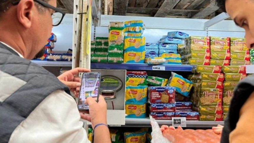 Fiscais do Procon Sergipe vistoriando prateleiras de estabelecimento comercial.