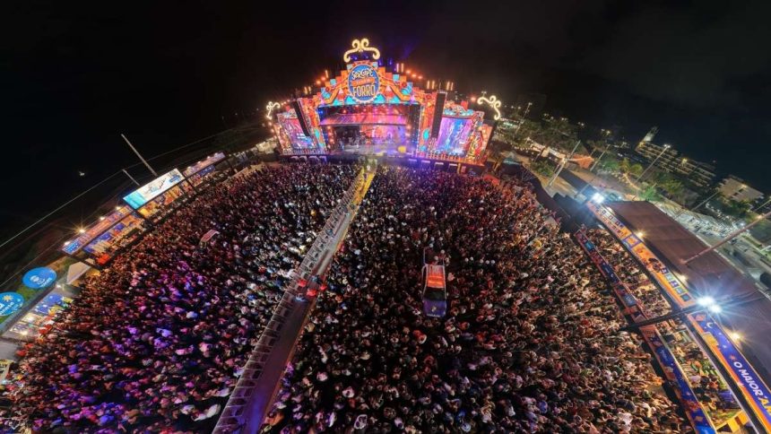 Grande estrutura de palco com painéis de LED iluminados durante apresentação de grupo folclórico na capital sergipana.