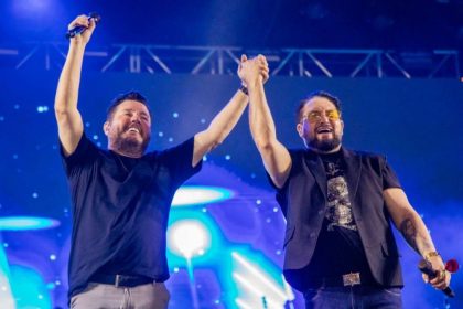 Foto de Bruno e Zezo no palco pegando nas mãos e levando ao alto