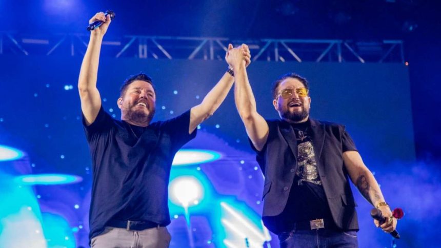 Foto de Bruno e Zezo no palco pegando nas mãos e levando ao alto