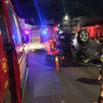 Equipes de trânsito e socorro atuando à noite em via urbana do Centro com veículo capotado na pista.