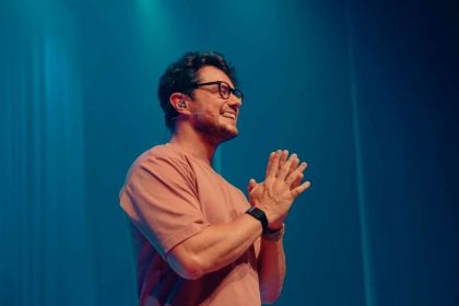 O evangelista Deive Leonardo no palco, falando ao microfone sob iluminação cênica marcante durante uma de suas pregações.