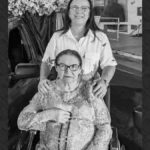 Foto de Dona Neusa sorrindo, uma senhora de cabelos brancos e expressão acolhedora, em retrato familiar de fundo claro.
