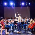 Crianças e adolescentes participando de aula de música com instrumentos de corda.