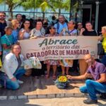 Grupo de manifestantes reunidos em frente à Câmara da Barra dos Coqueiros segurando uma faixa com os dizeres "Abrace o território das Catadoras de Mangaba".
