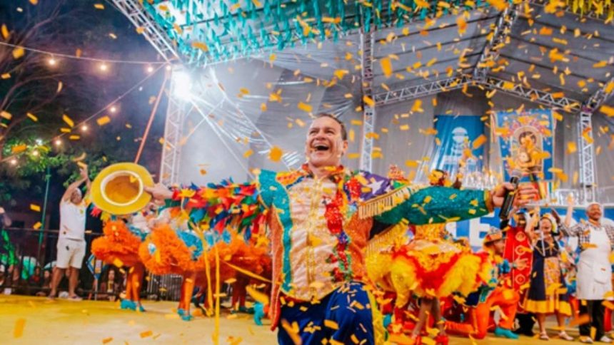 Brincantes da quadrilha junina Século XX sorrindo e dançando com trajes coloridos e caipiras estilizados na arena lotada do Centro de Criatividade.