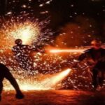 Centelhas e fumaça geradas pela queima de fogos tradicionais em uma rua de paralelepípedos durante festividade junina noturna em Sergipe