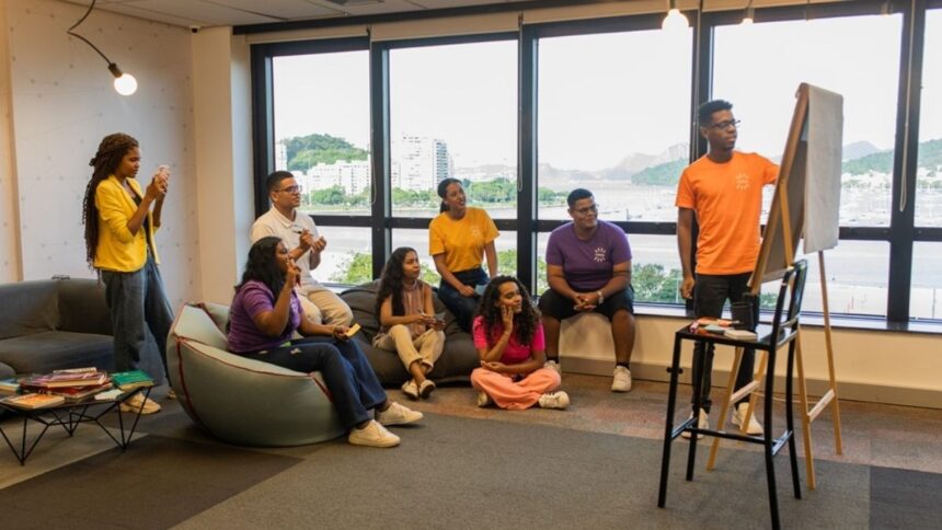 Jovem estudando no celular e computador em ambiente doméstico.