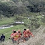 Equipe do Corpo de Bombeiros atuando em resgate em área de vegetação e pedras.